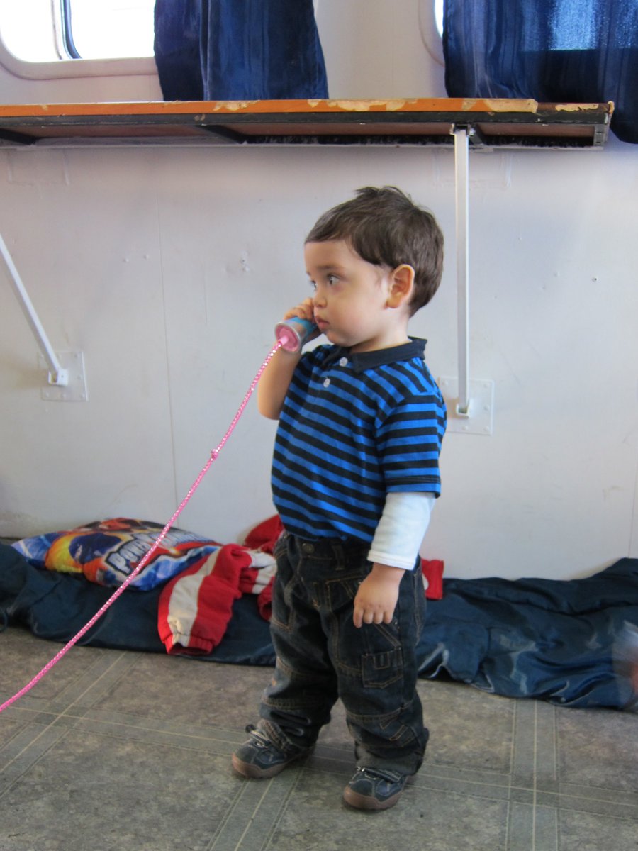 A toddler talking into a toy telephone